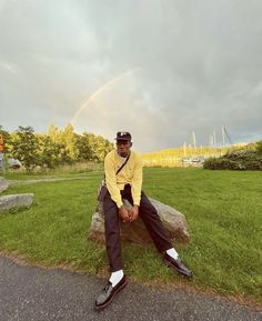 a man sitting on top of a rock in the grass