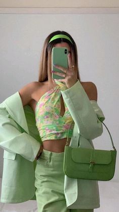 a woman taking a selfie with her cell phone in front of her face and wearing a green outfit