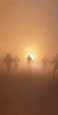 some people are walking in the fog and one is holding a light saber