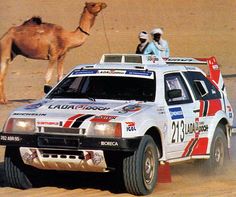 a car driving down a dirt road with a camel in the background