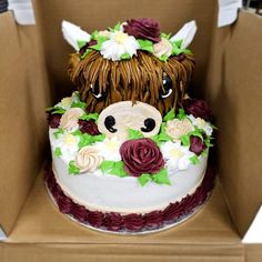 a cake in the shape of a cow with flowers around its head and eyes on top of a cardboard box