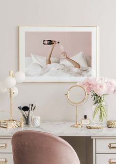 a white desk topped with a pink chair next to a mirror and vase filled with flowers