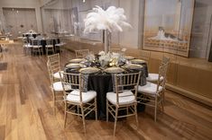 a room filled with tables and chairs covered in black table cloths next to pictures on the wall