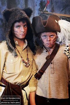 two young boys dressed up as pirates and one is wearing a bear hat with feathers on his head