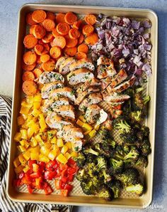 a tray filled with chicken, broccoli and carrots next to other vegetables