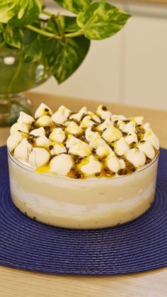 a cake with marshmallows on top sits on a blue mat next to a potted plant