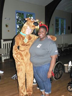 a woman standing next to a man in a dog costume