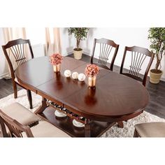 a dining room table with four chairs and vases on the top, in front of a window