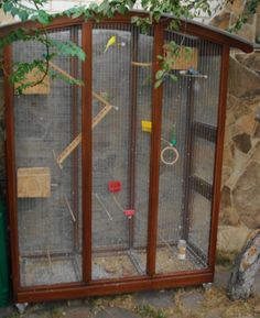 a large bird cage sitting next to a tree