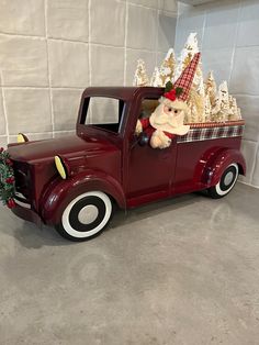 an old fashioned red truck with a santa clause on the back and christmas decorations in the bed