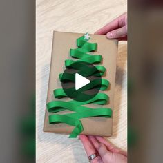 someone is wrapping a christmas present with green ribbon and a star on the top, while another person's hands are holding it