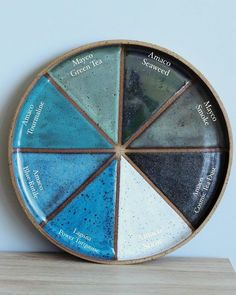 a plate with different colors on it sitting on top of a wooden table next to a white wall