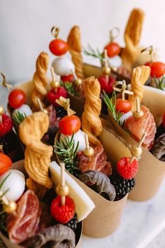 small trays filled with different types of appetizers and fruits on sticks, sitting on a table