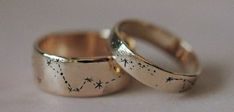 two gold wedding rings with stars on the inside and outside, sitting side by side