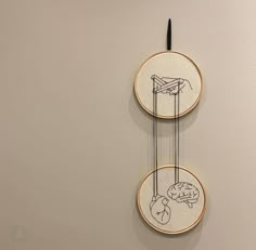 two embroidery hoop hanging on the wall next to each other, with one drawing of a person holding a kite