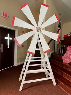 a white wooden windmill sitting on top of a red carpeted floor next to stairs