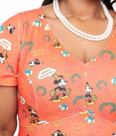 a woman wearing an orange mickey mouse top with pearls on her necklace and pearl necklace