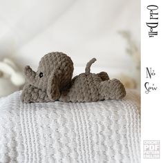 a crocheted elephant laying on top of a bed