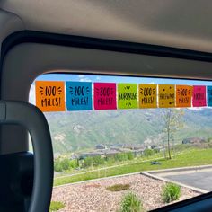 the view from inside a car looking out at mountains and houses with colorful signs on them