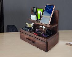 a wooden box with sunglasses, cell phone and other items in it on a table