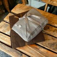 two folded towels sitting on top of a wooden table next to each other and tied with a ribbon