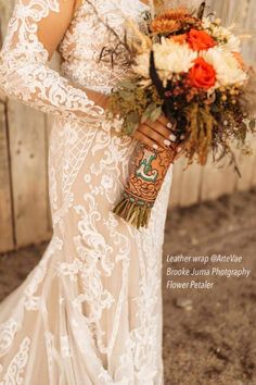 a woman in a wedding dress holding a bouquet and wearing a tattoo on her arm