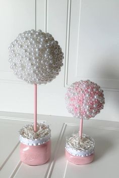 two pink and white vases with pearls on them sitting on a table next to each other