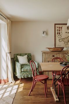 a dining room table with red chairs next to a green chair and a couch in the background