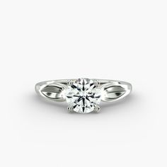 a white gold ring with a round cut diamond in the center, on a white background