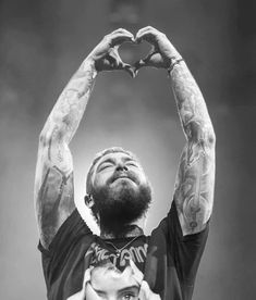 a man holding up his hands in the shape of a heart on top of his head