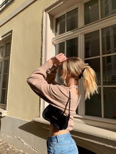 a woman standing in front of a window with her hand on her head and looking out the window