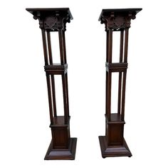 two tall wooden pedestals with carvings on the top and bottom, one holding a clock