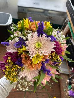 a bouquet of flowers is being held up by someone's hand in front of an oven