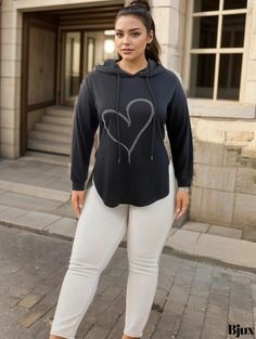 a woman standing in front of a building wearing white pants and a black hoodie