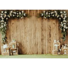 a wooden backdrop with white flowers and greenery on the side, along with chairs