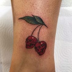 a tattoo with two cherries on the ankle