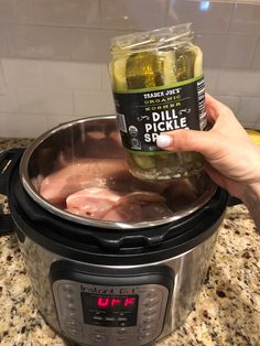 a person holding a jar of pickle in an instant pot