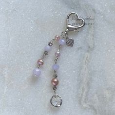 a key chain with beads and charms attached to it on a white marble slab background