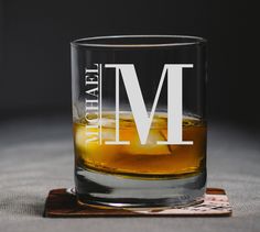 a shot glass with the letter m on it sitting on a coaster that says i am