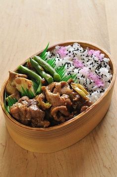 a wooden bowl filled with rice, meat and veggies next to green beans