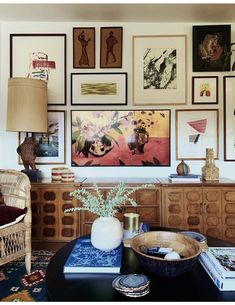 a living room filled with lots of pictures on the wall above a black coffee table