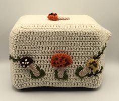 a crocheted purse with flowers and leaves on the front, sitting on a white surface