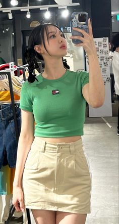 a woman taking a selfie with her cell phone in front of some clothing racks