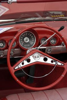 the interior of an old fashioned car with red leather and chrome trims, including steering wheel