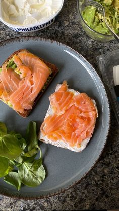 two pieces of bread on a plate with salmon and lettuce next to it