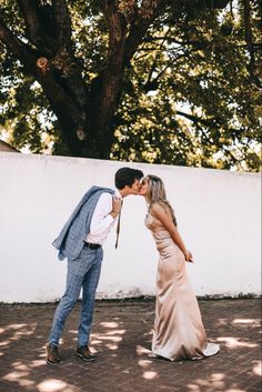 a man and woman kissing in front of a tree