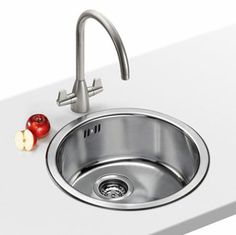 a stainless steel sink and faucet with red tomatoes on the countertop next to it