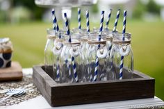 there are many glasses with blue and white striped straws in them on the table