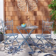 two chairs and a table in front of a wooden wall with a tree on it