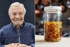 an older man sitting at a table next to a jar filled with food and smiling